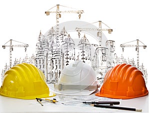 Safety helmet on engineer working table against sketching of building construction and high crane safety helmet on engineer