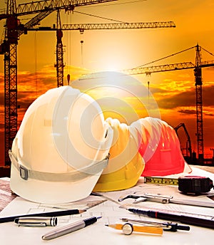 Safety helmet on engineer working table and construction site background