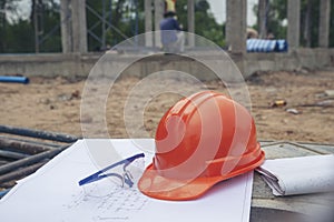 Safety helmet hard hat, blueprint, glasses, and drawings paper for engineer, safety officer or architect, place on wooden floor