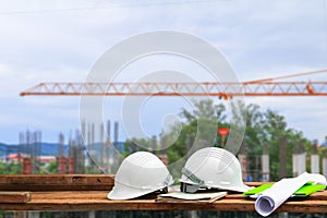 Safety helmet plastic and blueprint on wood with blur construction building site workplace background