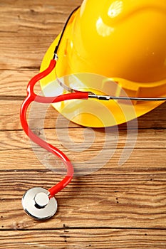 Safety Helmet with Stethoscope on Wooden Table