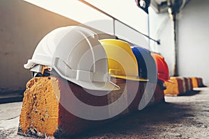 Safety helmet, white, yellow, blue and orange, placed on the cement floor in the construction site