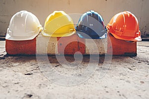 Safety helmet, white, yellow, blue and orange, placed on the cement floor in the construction site