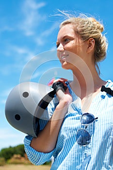 Safety, helmet and woman on blue sky for adventure, outdoor and thinking in countryside with a smile. Happy, person and