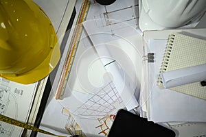 Safety helmets, blueprints and notebook on the engineering desks. Engineering tools, workspace concept