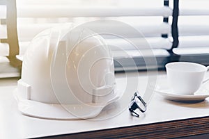 Safety helmets white and coffee cup on a wooden table.