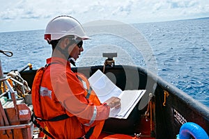 Safety officer, standing on an industrial ship, wearing overalls, a helmet, safety goggles and holding a clipboard with checklists