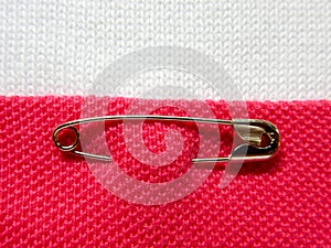 Safety pin on fabric background with note space