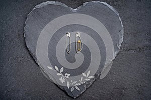 Safety pins on a heart made of slate symbolize pregnancy and family planning