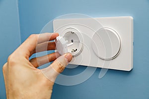 Safety plug for an electrical outlet, protecting a child from electric shock on a blue background