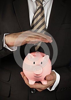 Safety of savings concept, businessman hold piggy bank