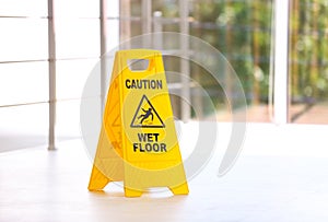 Safety sign with phrase Caution wet floor, indoors.