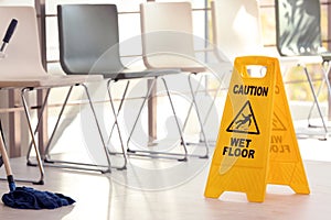 Safety sign with phrase Caution wet floor and mop