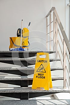 Safety sign with phrase Caution wet floor and mop bucket