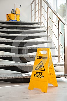 Safety sign with phrase Caution wet floor near stairs