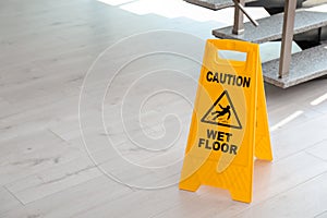 Safety sign with phrase Caution wet floor near stairs