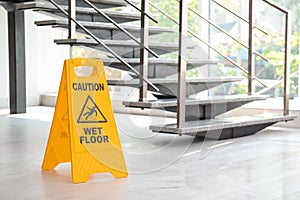 Safety sign with phrase Caution wet floor near stairs