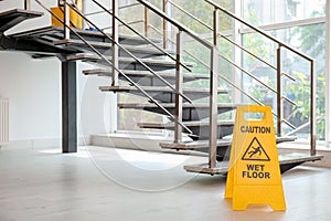 Safety sign with phrase Caution wet floor near stairs