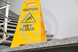 Safety sign with phrase Caution wet floor on stairs