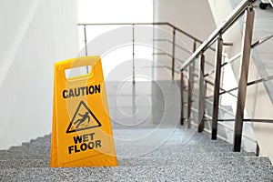 Safety sign with phrase Caution wet floor on stairs