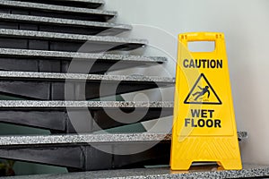 Safety sign with phrase Caution wet floor on stairs