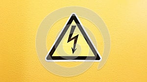 Safety sign yellow and black glued on a yellow wall. High voltage lightning in a triangle caution caution danger electricity death