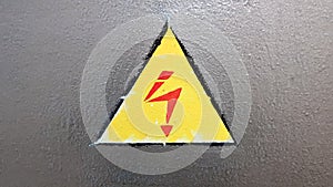 Safety sign yellow and red on a silver metal background. High voltage lightning in a triangle caution caution danger electricity