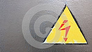 Safety sign yellow and red on a silver metal background. High voltage lightning in a triangle caution caution danger electricity