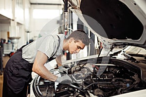 Safety sirst: a good-looking car mechanic is checking the engine