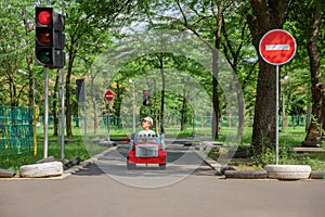 Safety traffic playground. Small boy driving toy car stops at traffic lights on playground child learn traffic rules