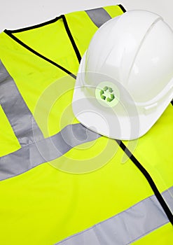 Safety vest and hard hat with recycling symbol over white background