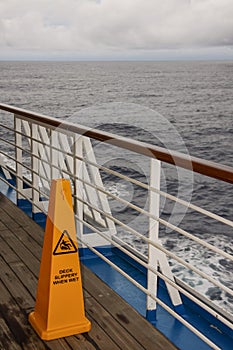 Safety warning marker Teak lined Promenade Deck of modern cruise ship.