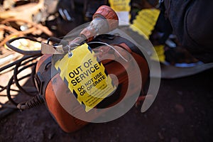 Yellow out of service tag attached on faulty damage defect of welding machine at construction site Perth, Australia photo