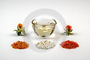 Safflower Carthamus tinctorius. Yellow, red dried petals, inflorescences, seeds and oil against a white background. Copy space photo