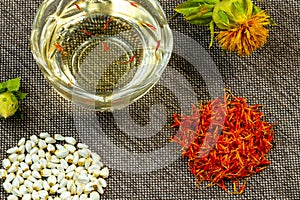 Safflower. Oil, seeds, bud, flower, red inflorescences of wild saffron. Close-up, gray fabric background. Ingredients for health,