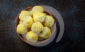 Saffron flavoured desiccated coconut ladoo in a wooden bowl