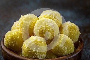 Saffron flavoured desiccated coconut ladoo in a wooden bowl
