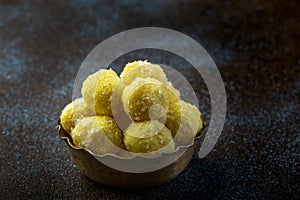 Saffron flavoured desiccated coconut ladoo in a wooden bowl