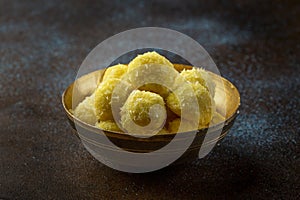 Saffron flavoured desiccated coconut ladoo in a wooden bowl