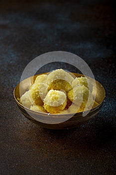 Saffron flavoured desiccated coconut ladoo in a wooden bowl