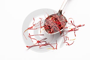 Saffron in a metal spoon. Spicy seasoning isolated on white