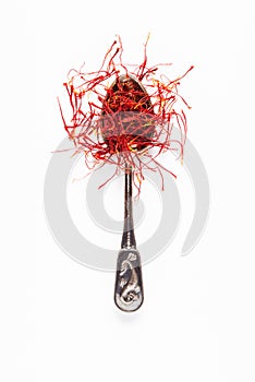 Saffron in a metal spoon. Spicy seasoning isolated on white top view