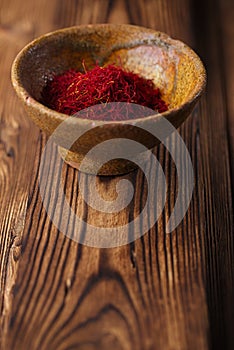 saffron spice in earthenware bowl on old textured wooden background