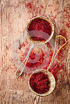 Saffron spice in rustic sieve on old wooden background