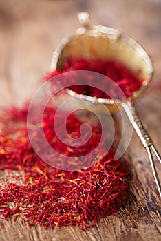 Saffron spice in rustic sieve on old wooden background