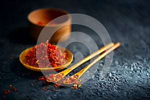 Saffron spices. Saffron on black stone table in a wood bowl and a spoon