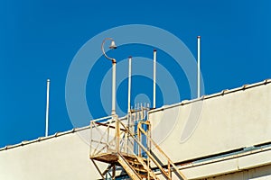 Saftey access ladder on side of building or parking structure in downtown urban city with poles and surveilance camera