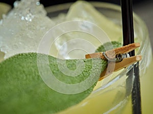 Sage leaf attached with decoration clip to a straw on a rack of ice in a drinking glass