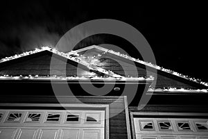 Sagging Christmas lights outdoors on a house that have come loose from the wind.
