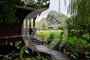 Sahded slabstone bridge to aged Chinese building in lotus lake